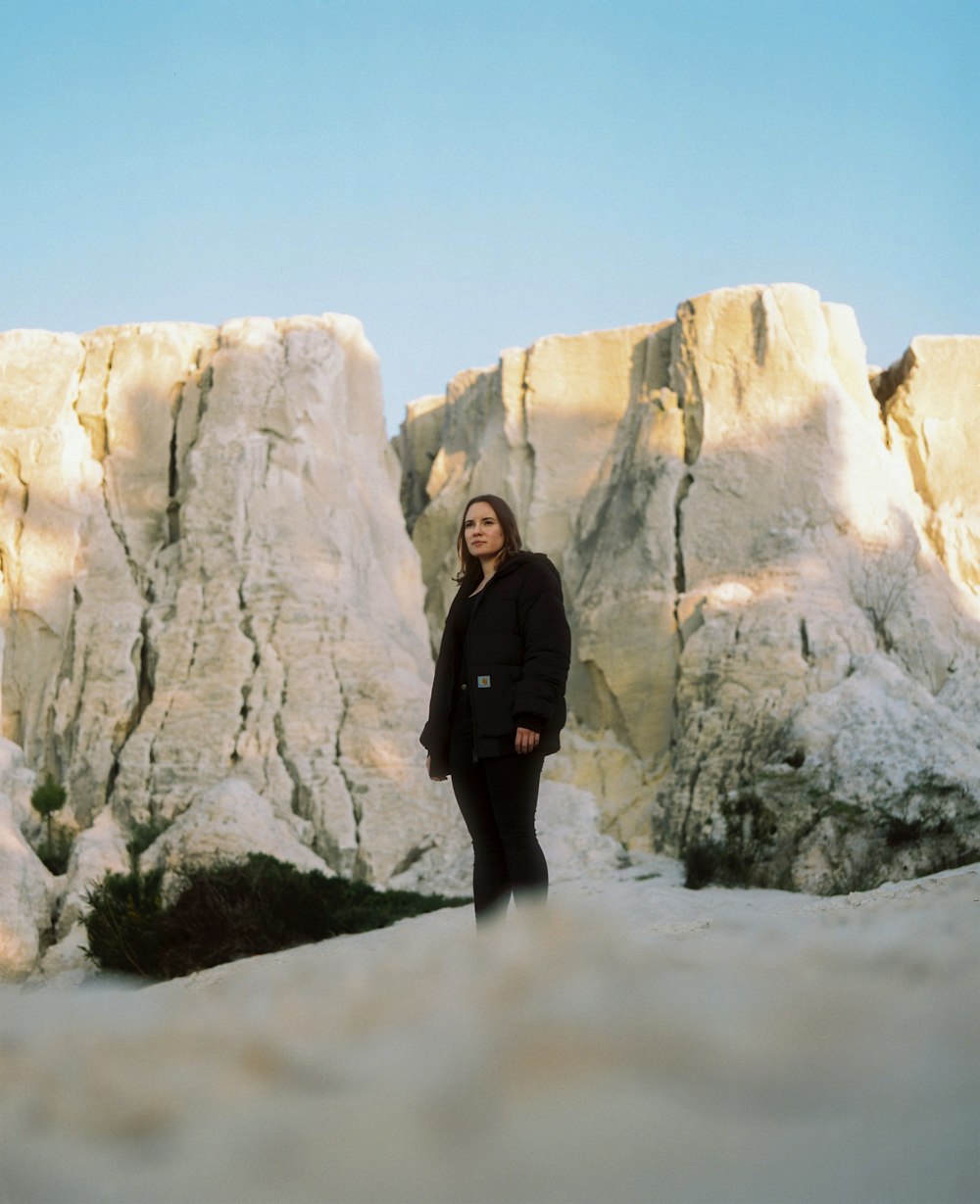 woman in black coat standing on white snow covered ground during daytime