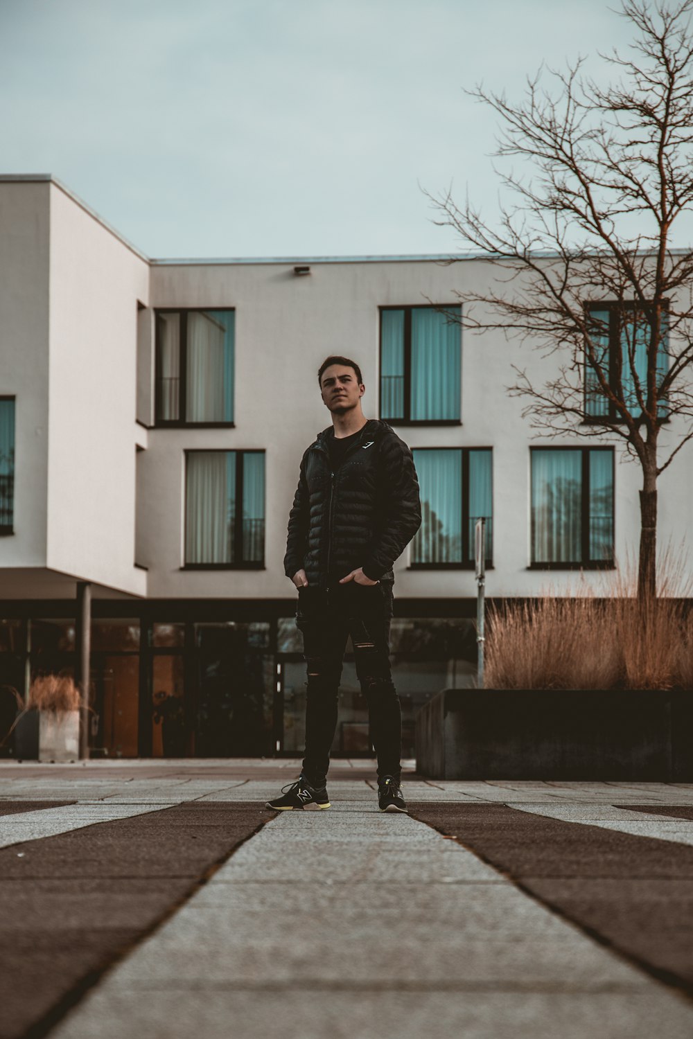 man in black jacket standing on sidewalk during daytime