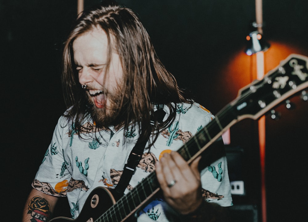 man in white and black crew neck t-shirt playing guitar