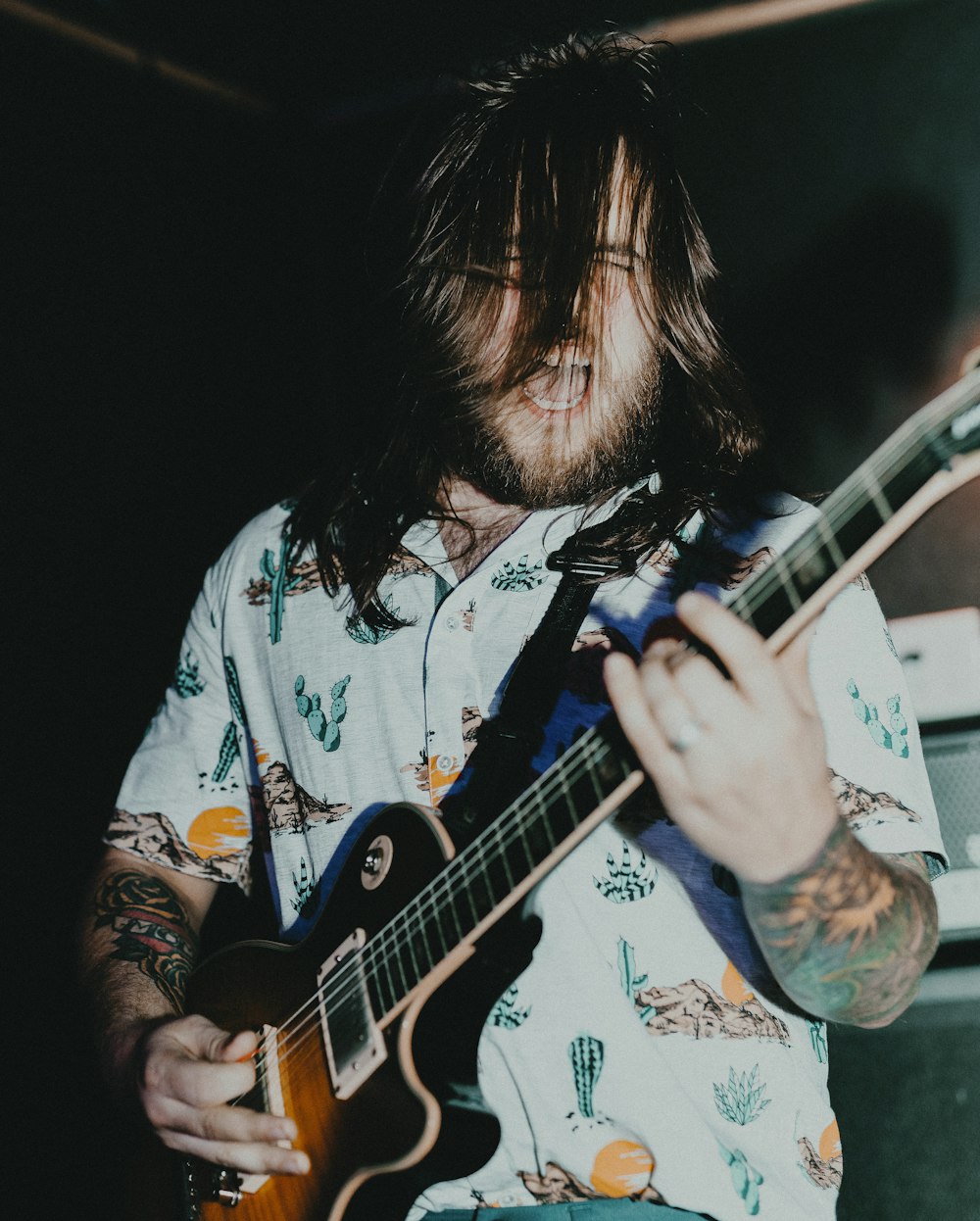 man in white red and green floral button up shirt playing guitar