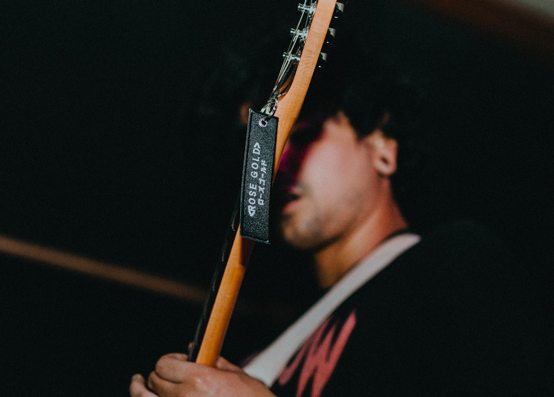 man in black shirt holding brown electric guitar