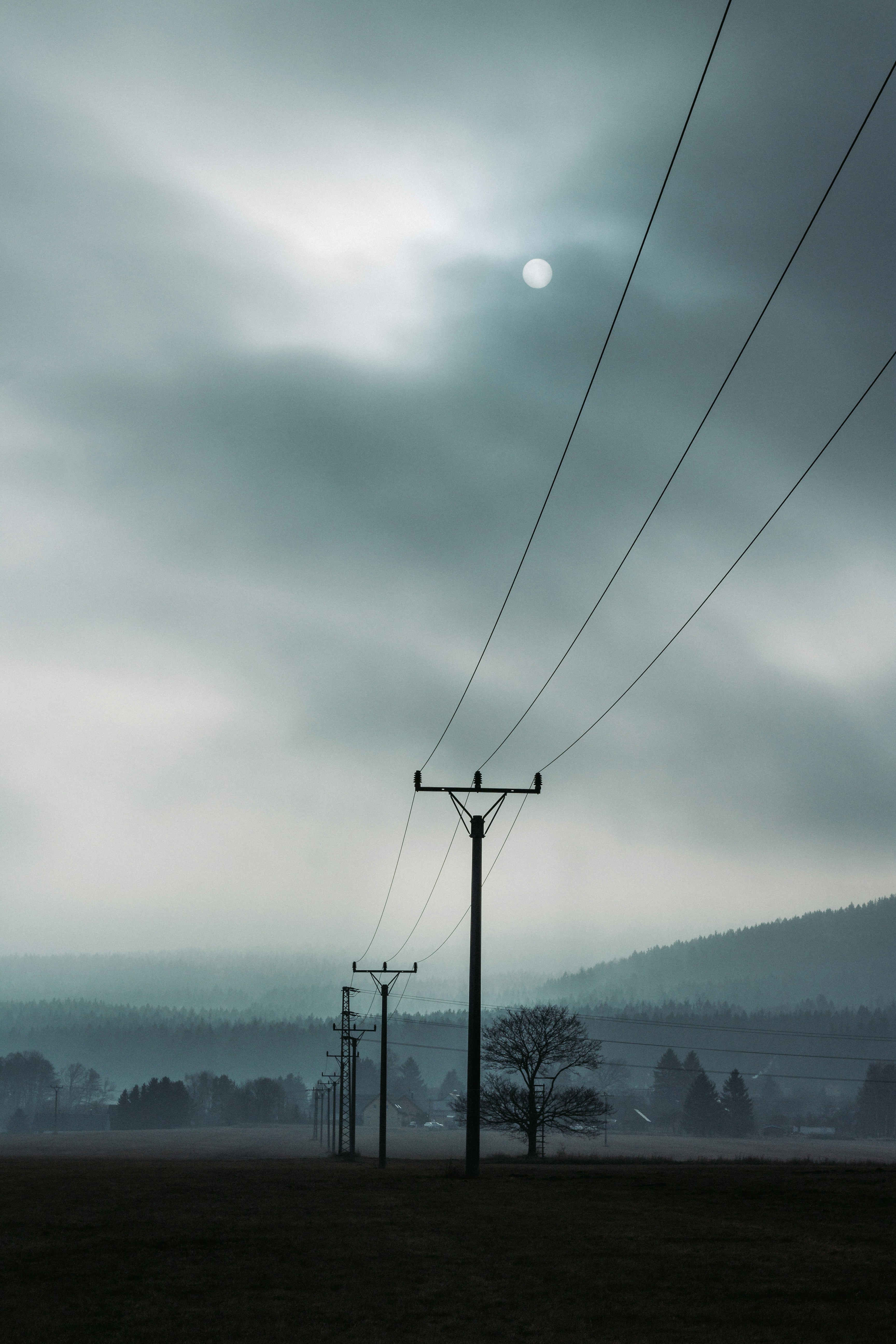 poteau électrique noir sous des nuages blancs pendant la journée