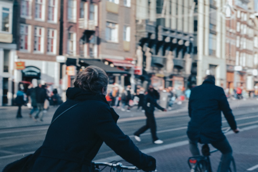 man in black jacket riding bicycle on street during daytime