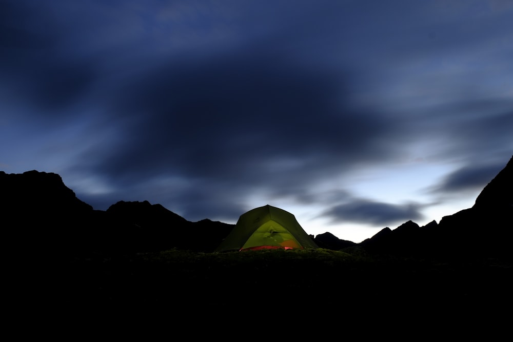 green tent on brown field under gray clouds