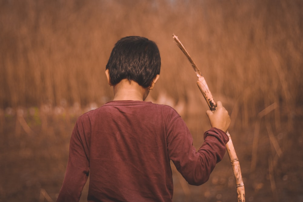 man in brown long sleeve shirt holding brown stick