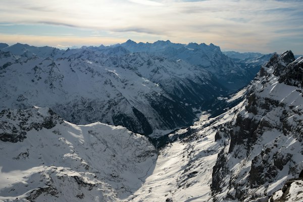 A winter panorama from high on the Titlis side looking down a deep, snow-covered U-shaped valley ringed by peaks
