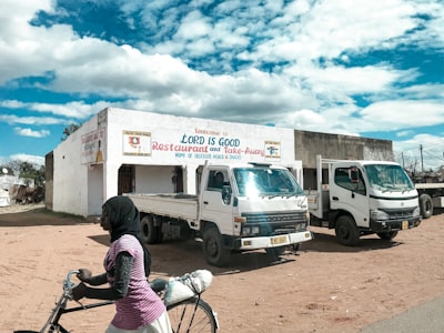 man in black and red plaid shirt riding on bicycle near white van during daytime malawi teams background