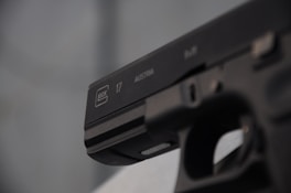 Close-up of a custom 1911 handgun resting on a wooden workbench, highlighting its detailed craftsmanship and finish.