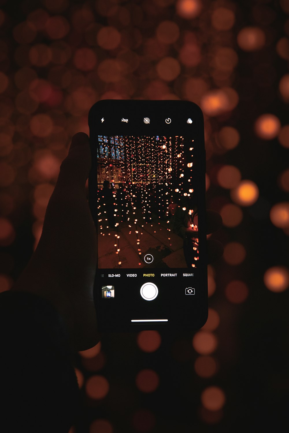 person holding iphone taking photo of city lights