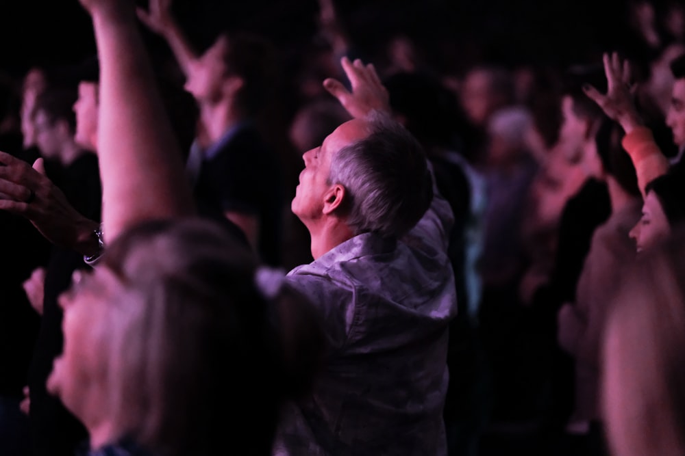 man in gray shirt raising his hands