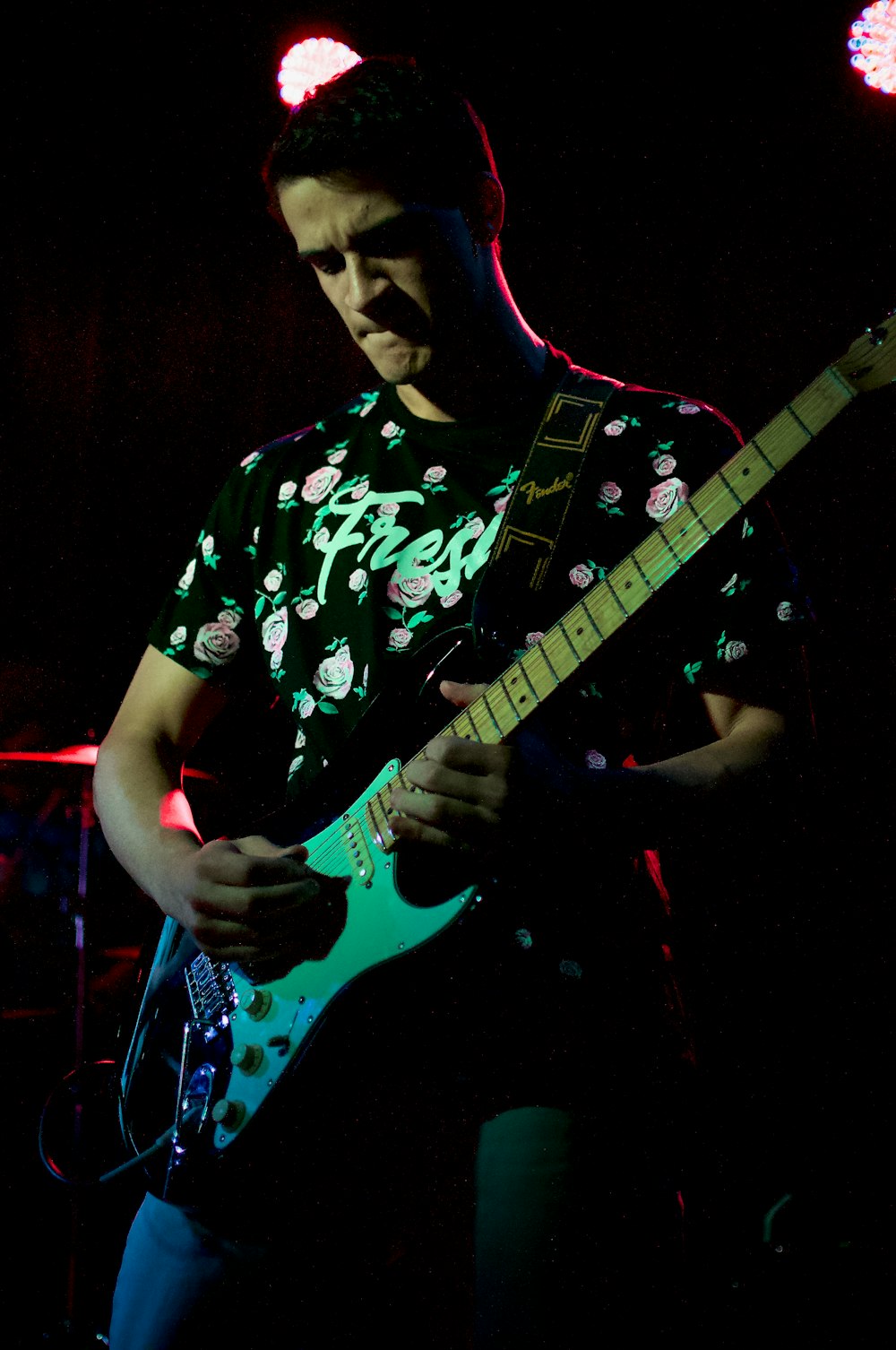 man in black and white floral crew neck t-shirt playing electric guitar