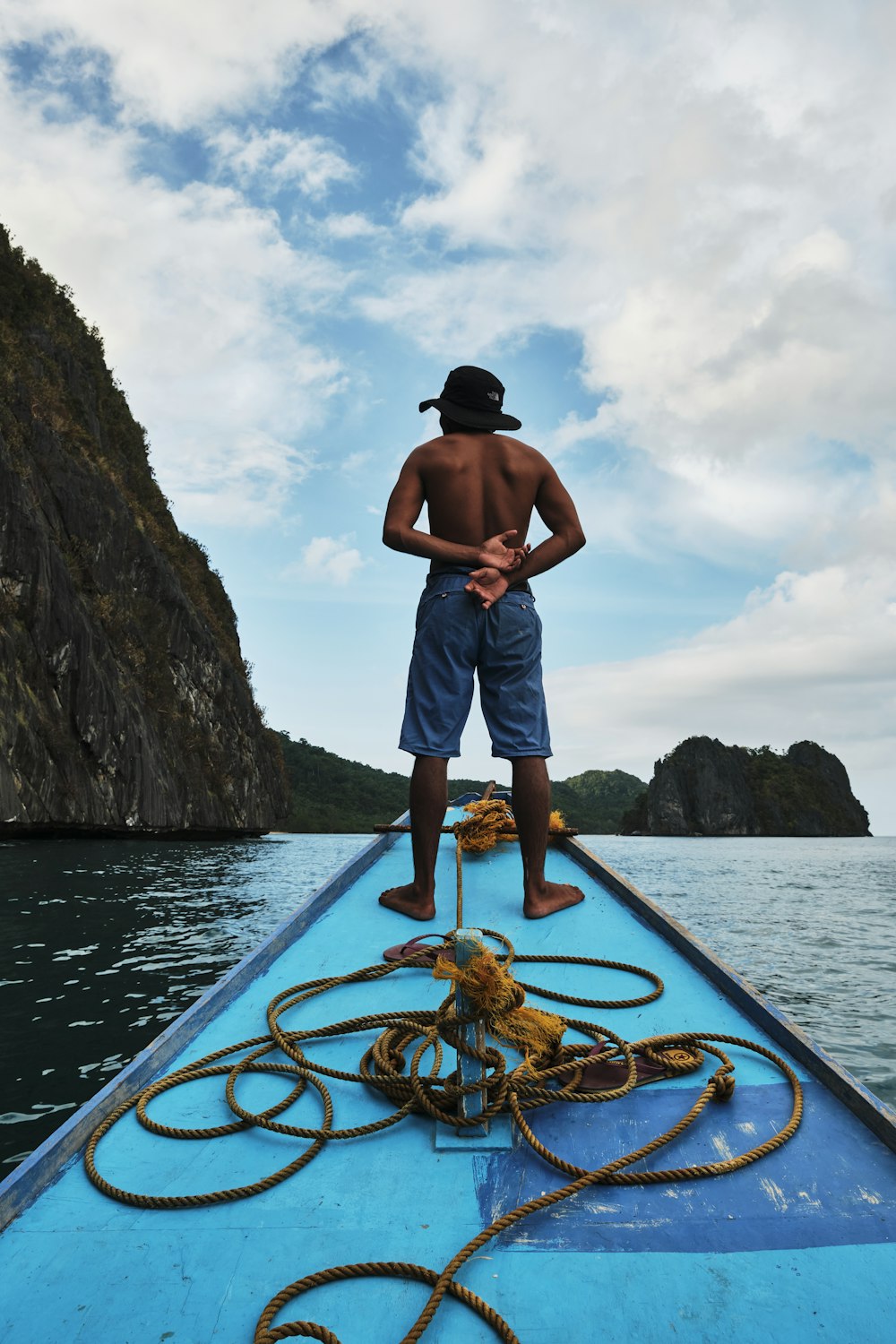 man in blue shorts standing on blue kayak during daytime