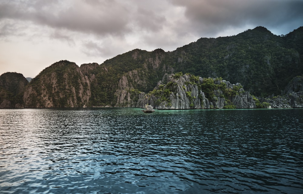 green mountain beside body of water during daytime