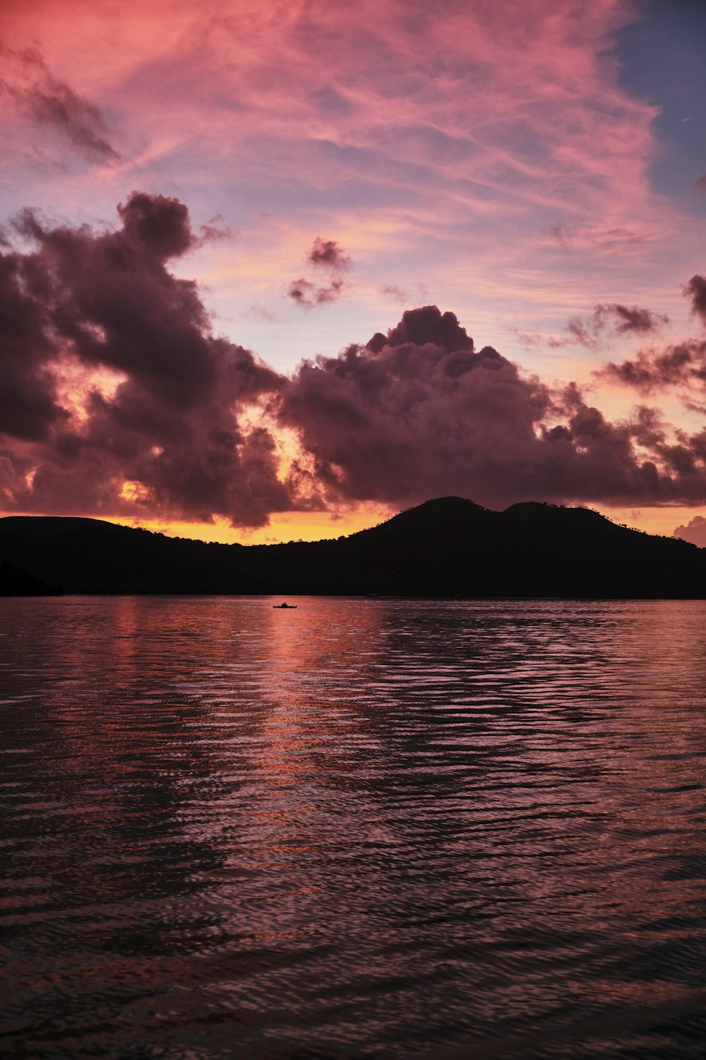 silhouette of mountain near body of water during sunset