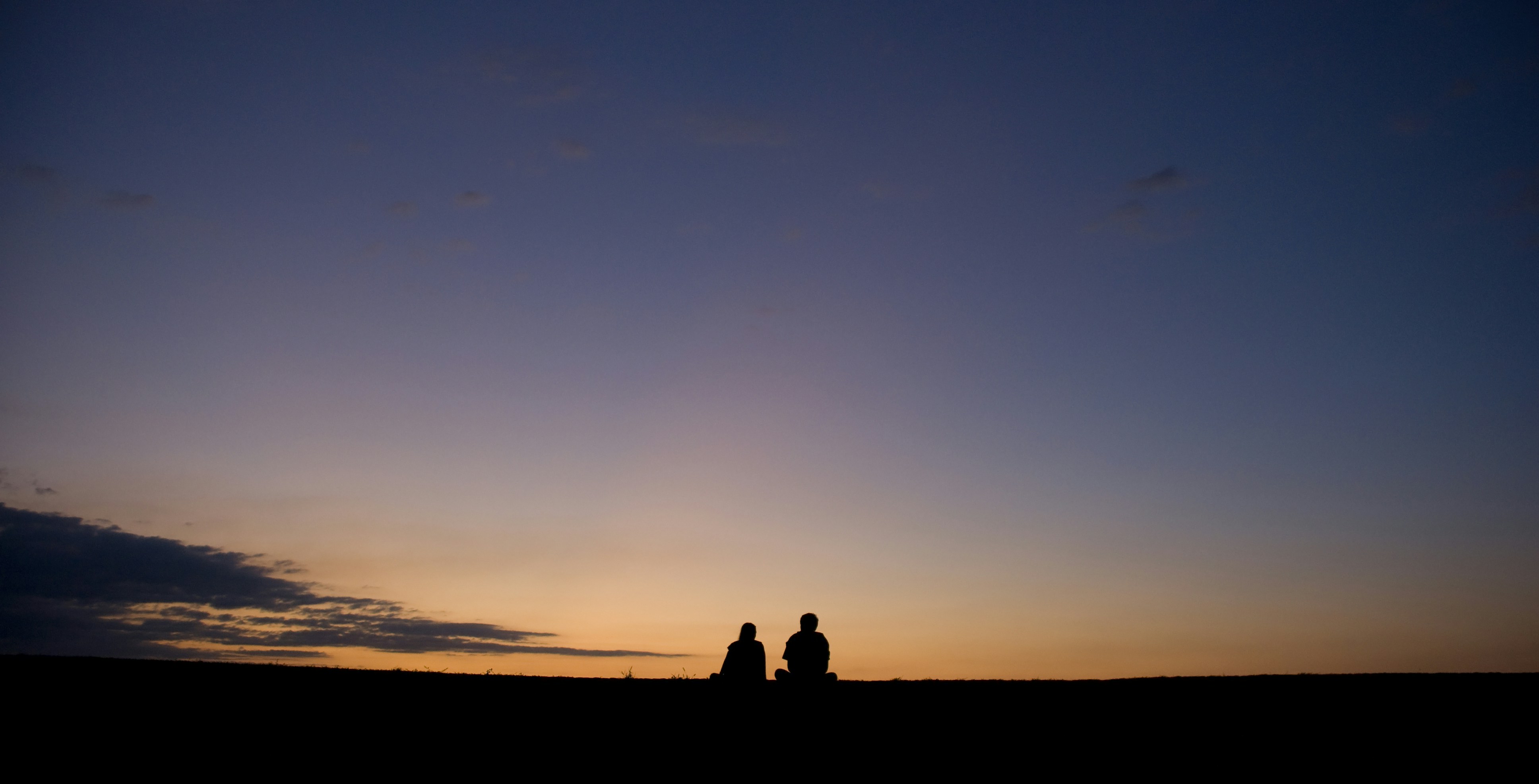 silhouette di 2 persone in piedi a terra durante il tramonto