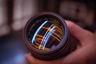 Close-up of a sleek optical lens with subtle orange light reflecting off its surface.