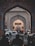 An ornate archway with intricate designs frames a bustling street leading to the City Palace of Jaipur. Cars, motorbikes, and pedestrians are visible, conveying a sense of activity and movement. The historic architecture is adorned with detailed patterns, and a sign indicates the entrance to the museum.
