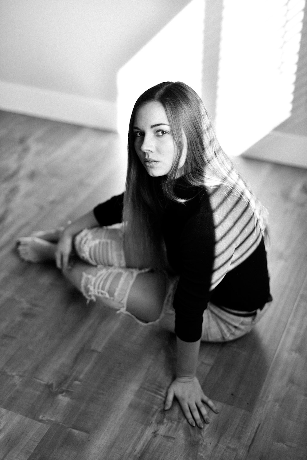 woman in white and black striped long sleeve shirt and black pants sitting on floor