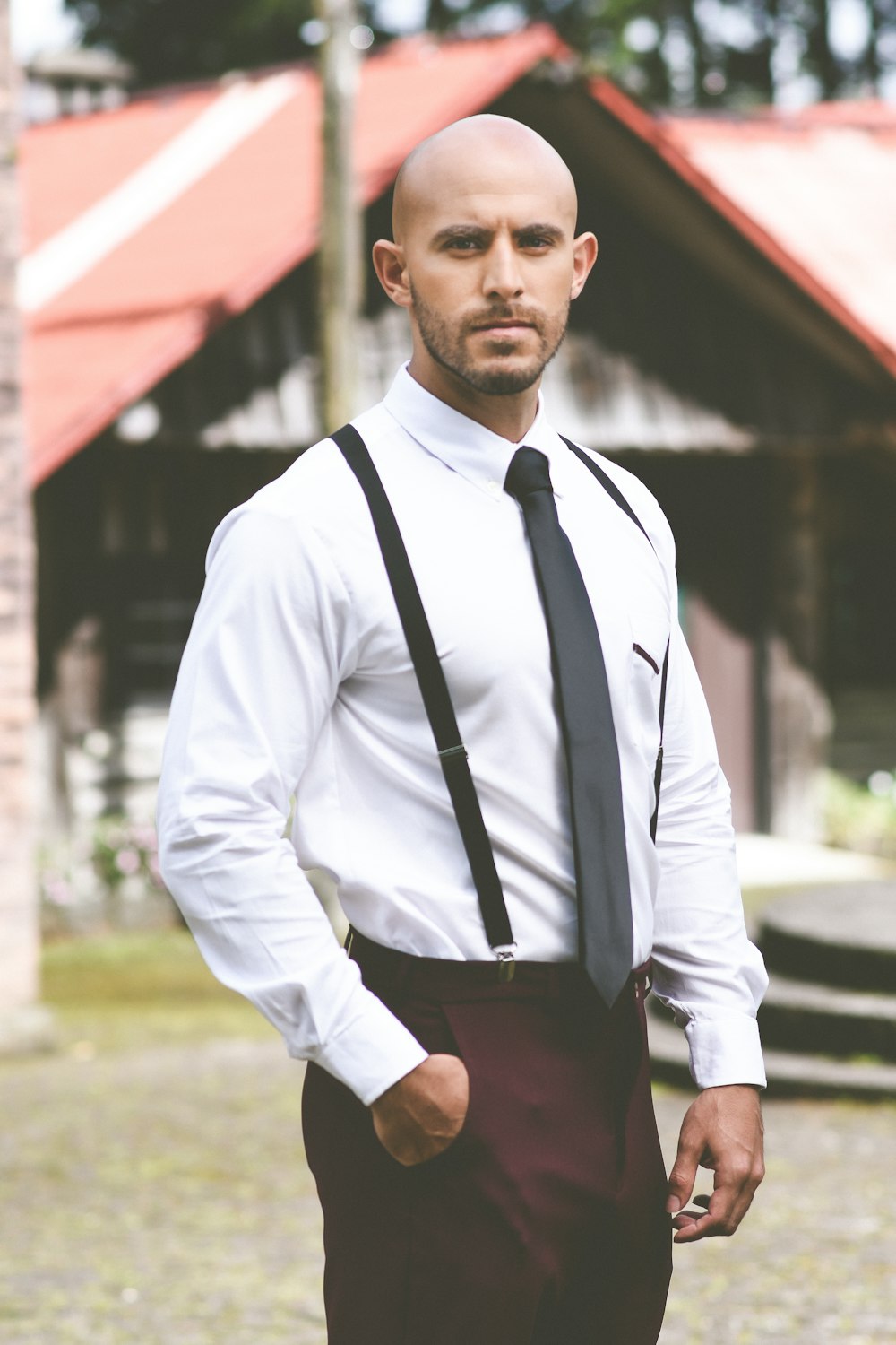 man in white dress shirt and black pants standing near red umbrella during daytime