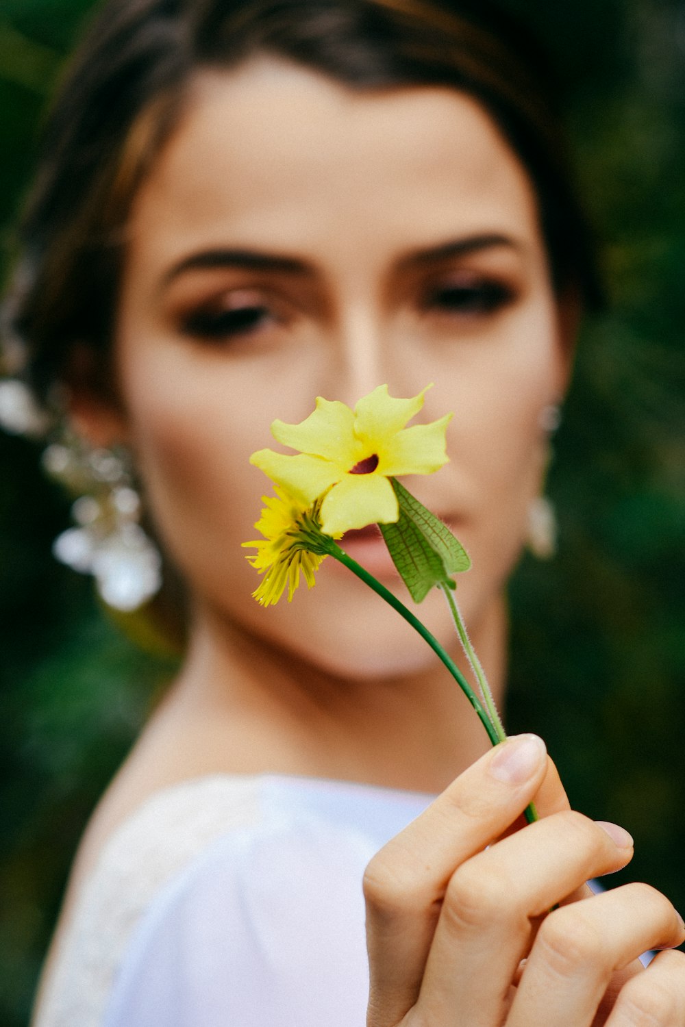 mujer en vestido blanco sosteniendo flor amarilla