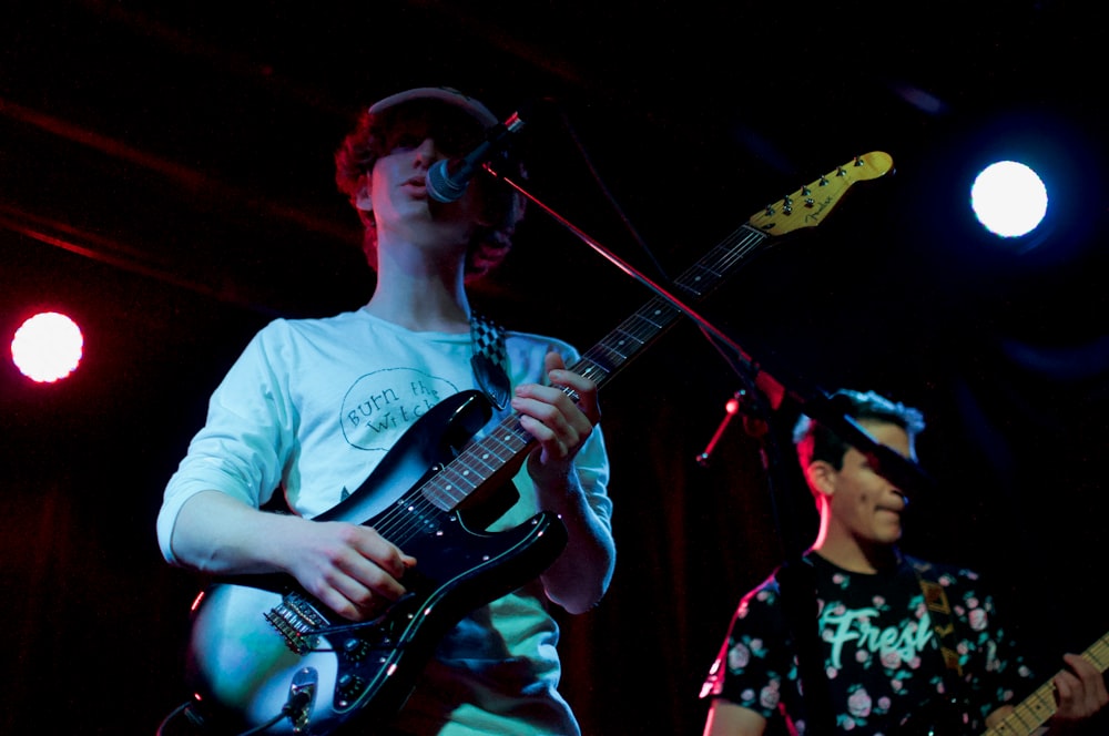 man in white crew neck t-shirt playing electric guitar