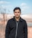 man in black zip up jacket standing on brown field during daytime