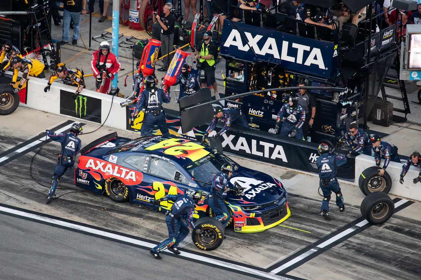 Pit crew servicing a stock car during a NASCAR race pit stop