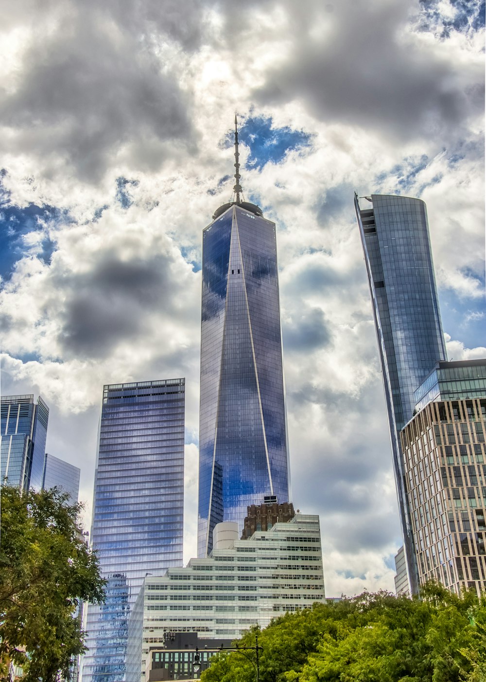 Edificio de gran altura gris y azul bajo nubes blancas durante el día