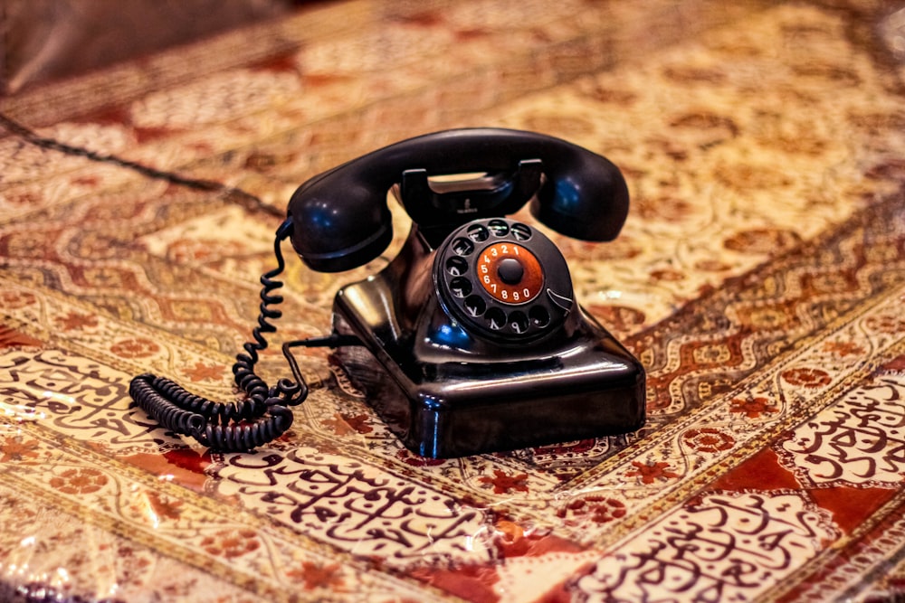 black rotary telephone on brown and white textile