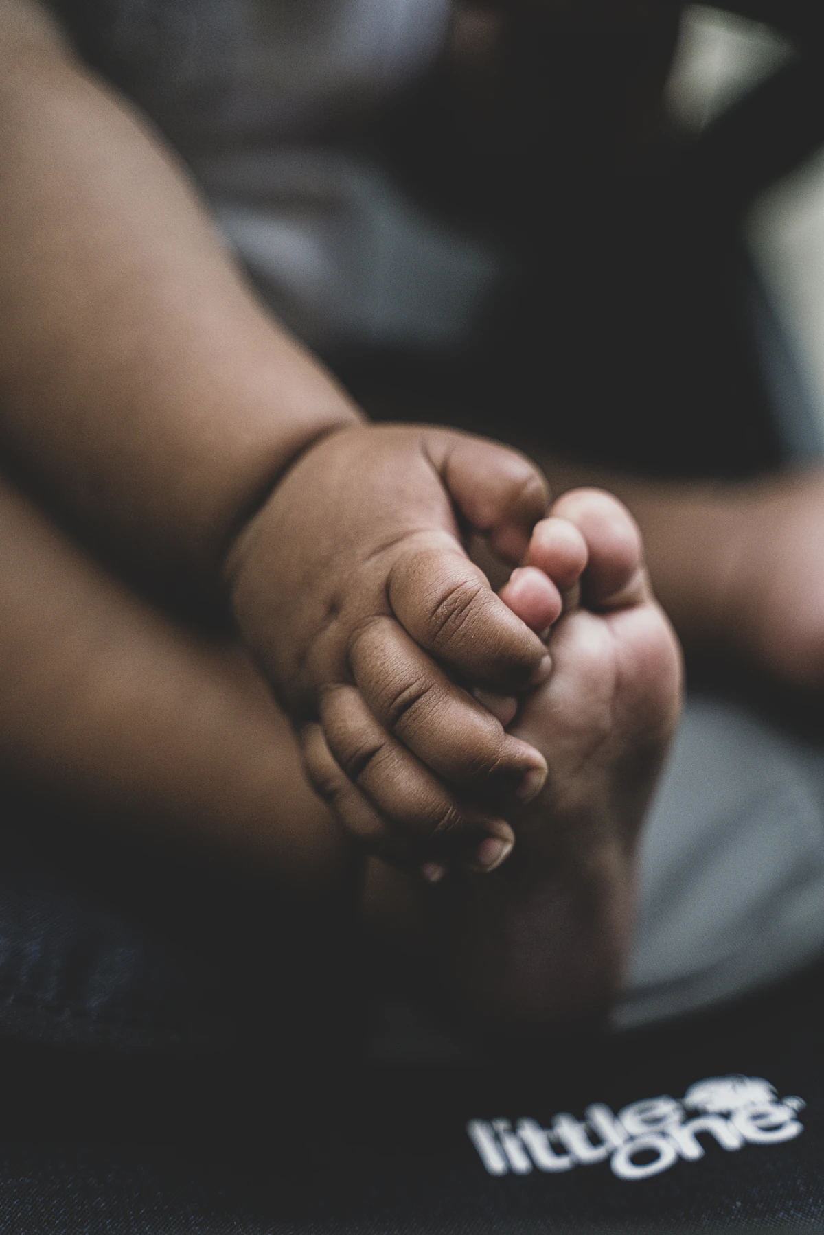 Orang dewasa memegang kaki mungil seorang bayi.