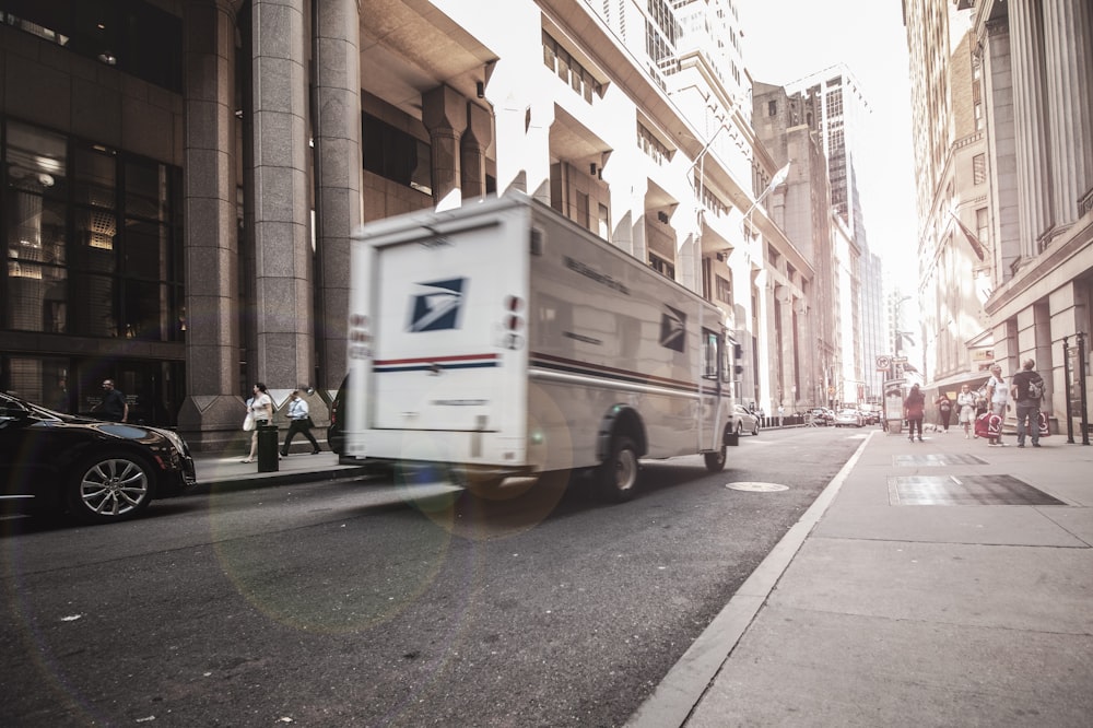 van branca estacionada ao lado do edifício de concreto marrom durante o dia