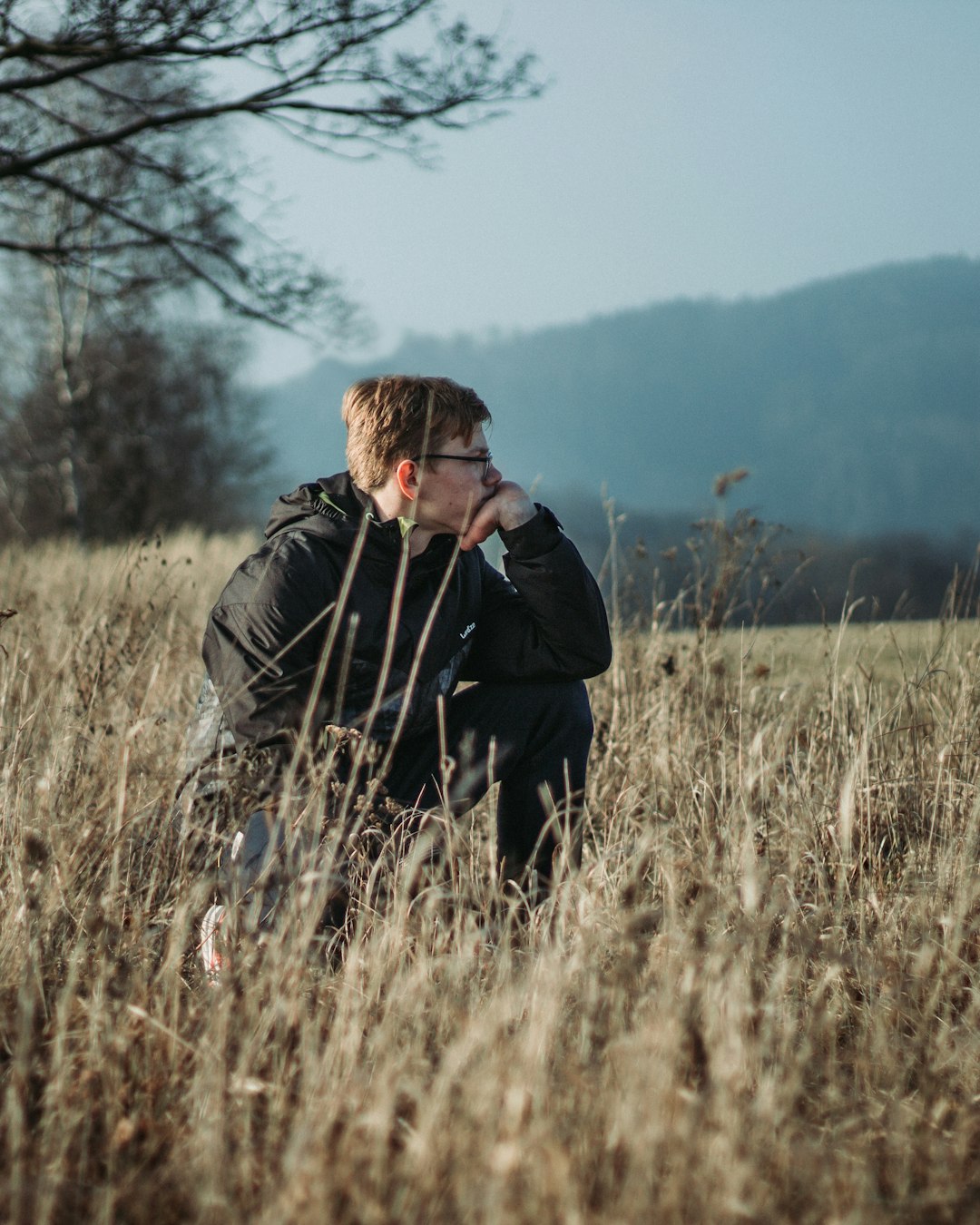 man in black jacket standing on brown grass field during daytime