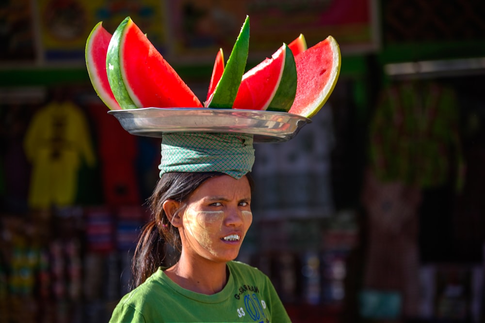 woman in green crew neck shirt holding sliced watermelon