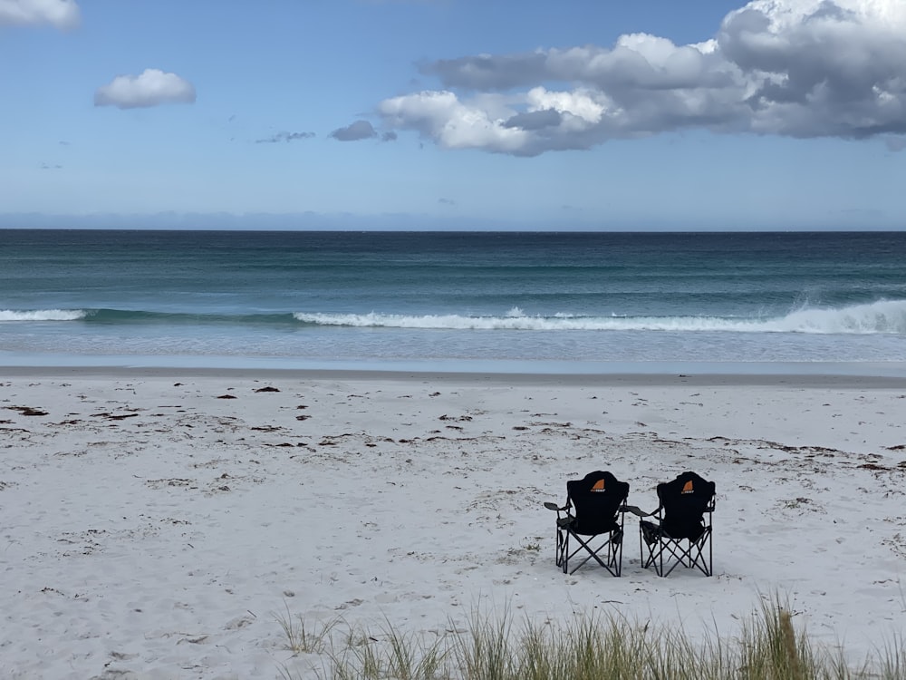 2 people sitting on camping chairs on beach during daytime