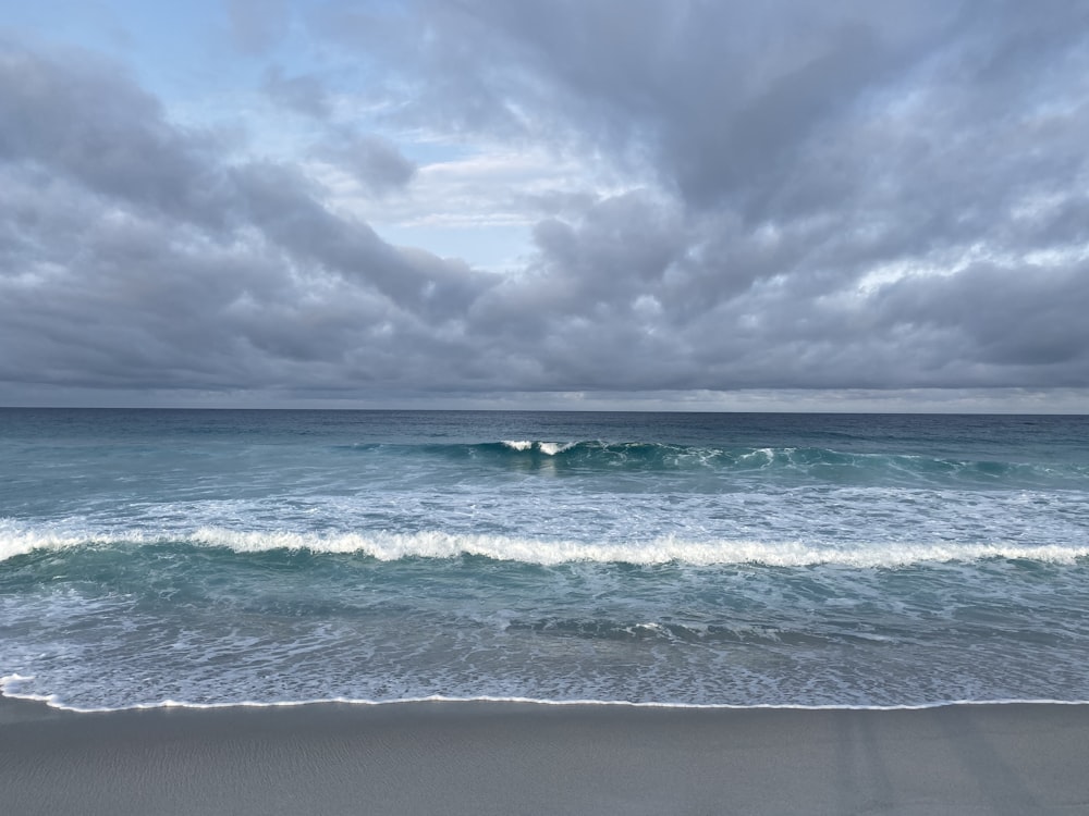 people swimming on sea under white clouds during daytime