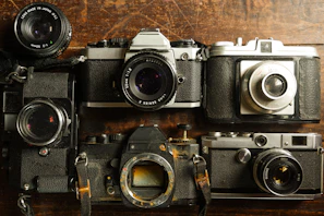 Vintage film cameras arranged on a rustic surface, evoking classic photographic charm.