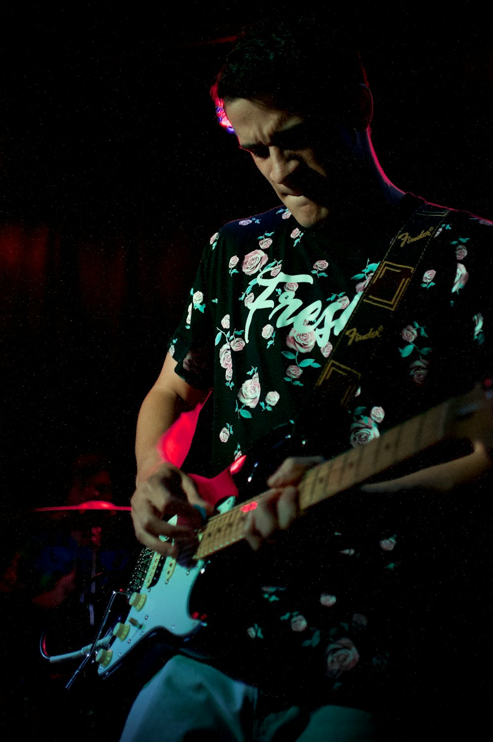 man in black and white floral shirt playing electric guitar