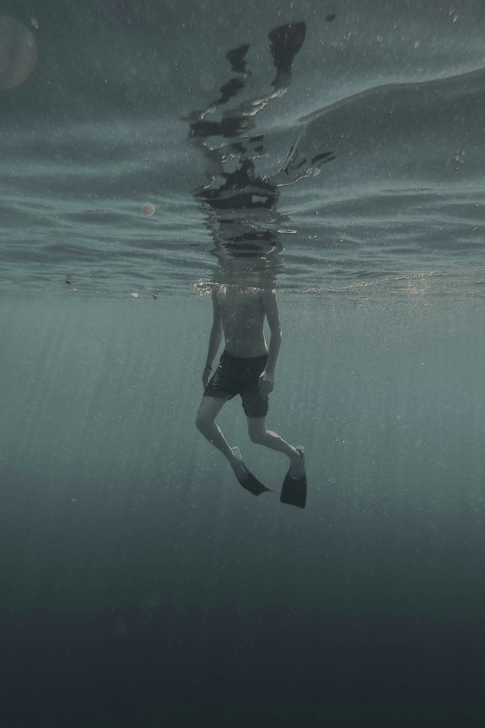 man in black shorts swimming in water