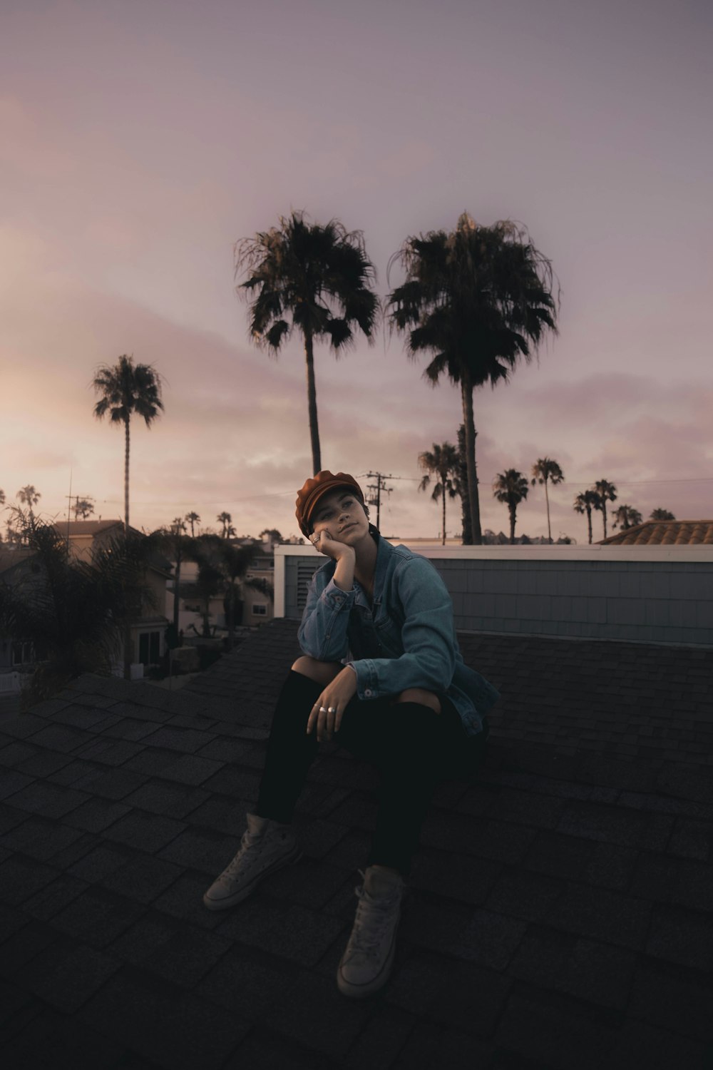 man in blue dress shirt and black pants sitting on gray concrete pavement during daytime