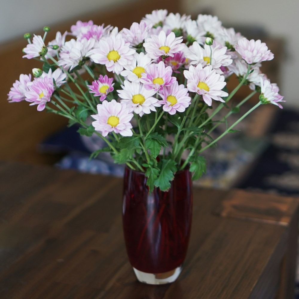 white and purple flowers in red glass vase
