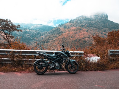 A sleek motorcycle parked on a scenic road with green hills in the background.