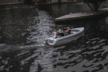 A group of friends laughing on a small boat, lines in the water