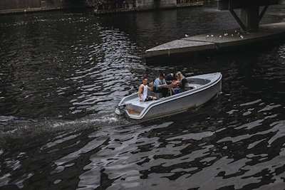 A group of friends laughing on a small boat, lines in the water