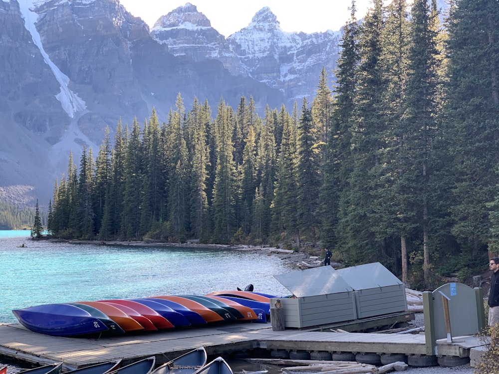 red and white boat on dock near green trees and mountain during daytime