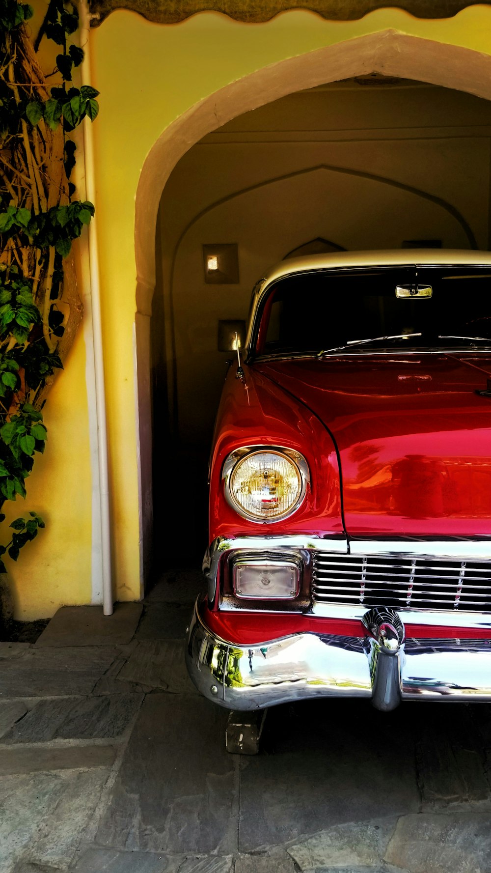 red car parked beside yellow painted wall