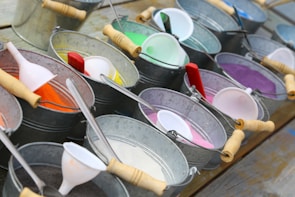 A collection of sand cans arranged on a wooden shelf, showcasing colors from white to deep brown.
