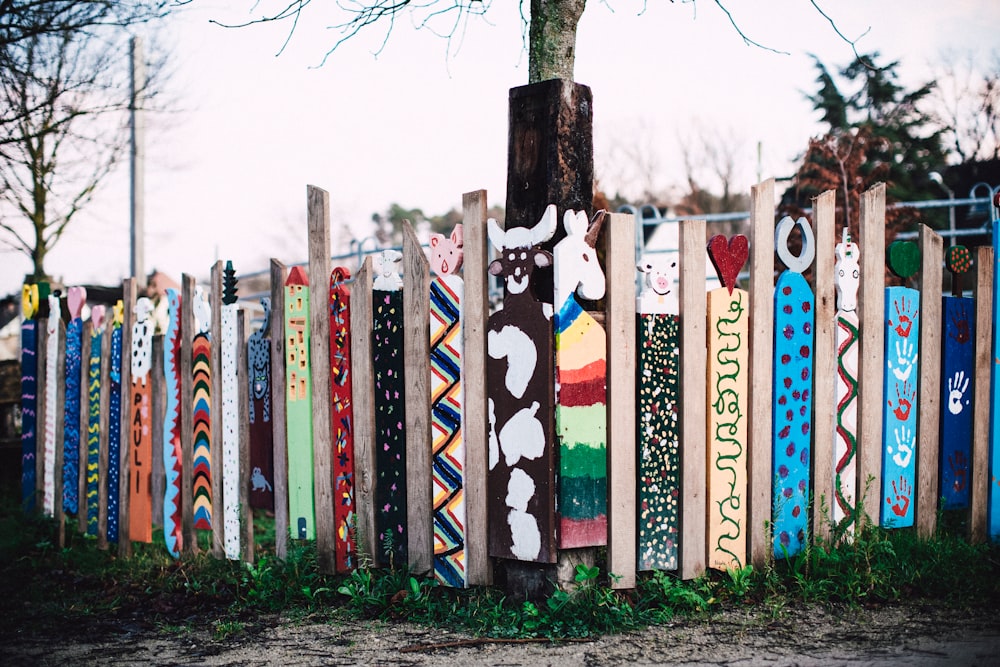 multi colored wooden fence near trees during daytime