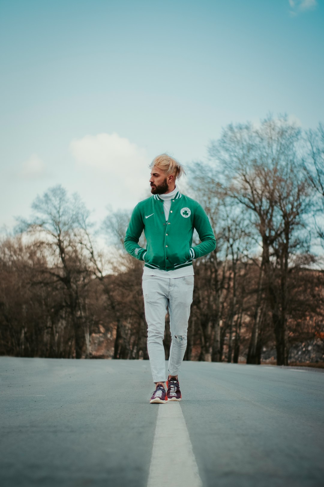 man in green zip up jacket and gray pants standing on snow covered ground during daytime