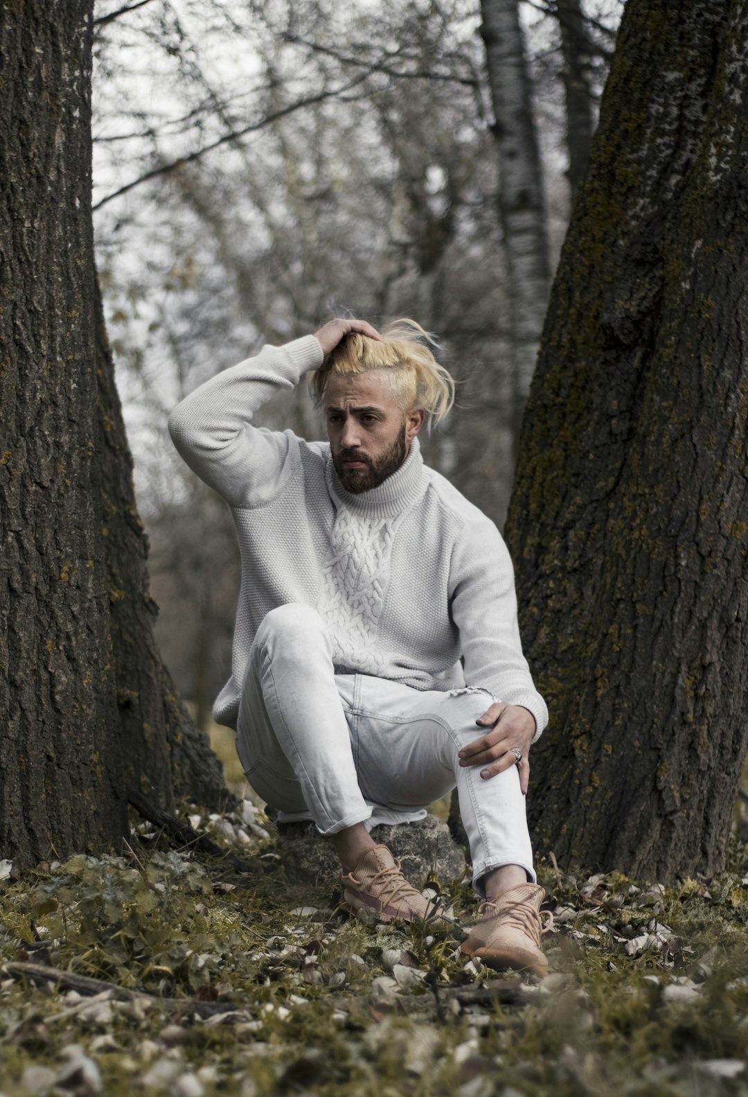 woman in gray sweater sitting on brown tree trunk during daytime