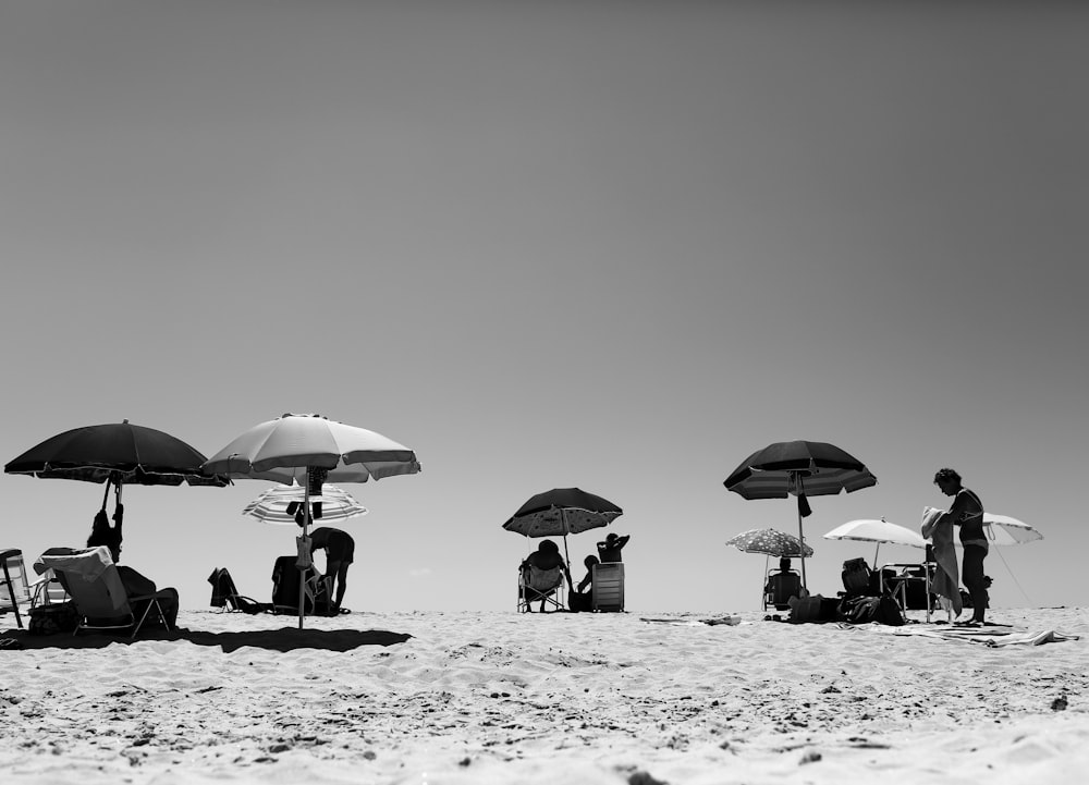 grayscale photo of 2 people under umbrella walking on beach